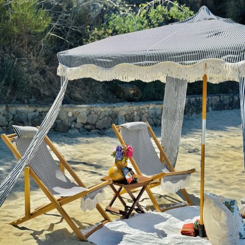 Nestled by rocky cliffs, this shaded cabana with cozy details invites you to a peaceful seaside escape.