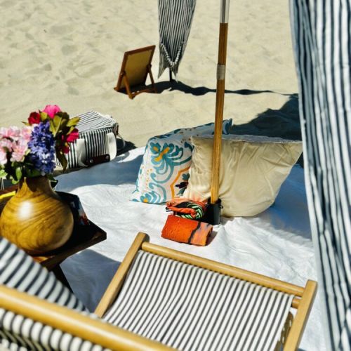 Soft pillows, floral touches, and breezy cabana shade create a dreamy beachside escape.