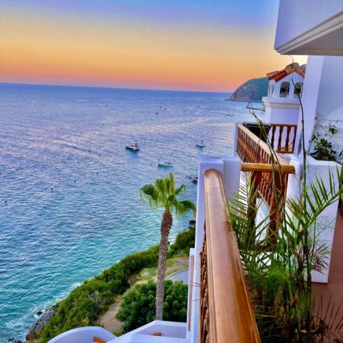 - Watch vibrant sunsets melt into the horizon from your private oceanfront balcony
- Gaze at a tranquil coastline dotted with boats, lush palms, and coastal cliffs
- Morning coffee or evening wine, this balcony view is pure vacation bliss