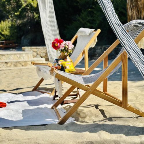 Kick back on striped loungers with snacks and flowers under a breezy cabana on soft beach sands.