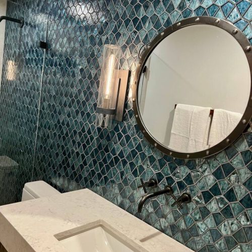 - Stunning sapphire toned tile backsplash adds a bold, stylish touch to this spa bath
- Industrial style mirror and lighting bring contrast to the sleek quartz vanity
- Matte black wall mounted fixtures complete the modern, exclusive look