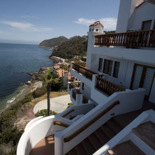 Whitewashed cliffside retreat with sweeping terraces and breathtaking ocean and mountain views.